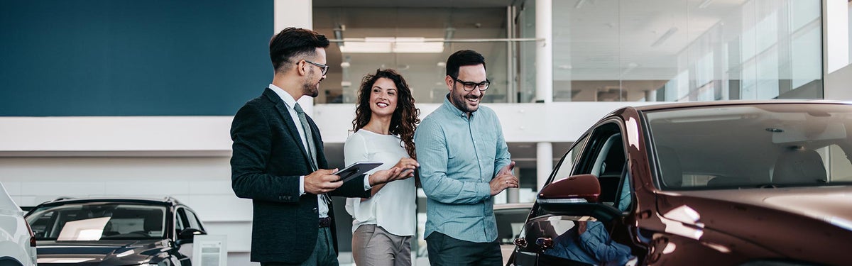 A couple speaking with a sales professional in an automotive showroom